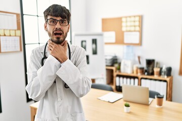 Sticker - Hispanic man with beard wearing doctor uniform and stethoscope at the office shouting and suffocate because painful strangle. health problem. asphyxiate and suicide concept.