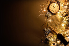 New Years Eve Holiday Background With Fir Branches, Clock, Christmas Balls, Champagne Bottle, Gift Box And Lights