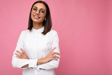 Photo shot of beautiful positive smiling young brunette woman wearing casual clothes and stylish optical glasses isolated over colorful background looking at camera