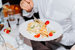 © Sergio - Man eating tomato salad, crackers, greens from a plate indoors, close-up. Festive feast concept. selective focus on food