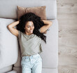 © kite_rin - Young woman relaxing at home lying on sofa. African american girl resting in her room. Enjoy life, rest, relaxation, wellbeing, lifestyle, people, recreation concept