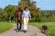 woman with dog and horse walking