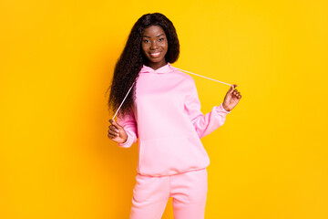 Wall Mural - Photo portrait of african american girl pulling hoodie strings laces isolated on vivid yellow colored background