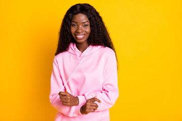 Sticker - Photo portrait of african american girl pulling hoodie strings laces isolated on vivid yellow colored background