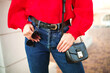 © ClaudiK - Blogging and street style concept. Autumn and winter outfit details. Young woman wearing casual blue jeans with red blouse and holding a black leather bag. Outdoors, selective focus.