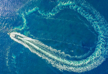 A high-speed boat or yacht maneuvers on the surface of the sea or ocean. Aerial view.