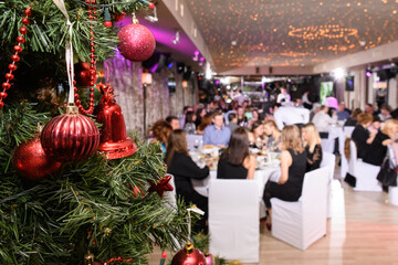 Close up of decorated christmas tree in the restaurant. New Year's corporate event of a large company. Blurred background, selective focus.