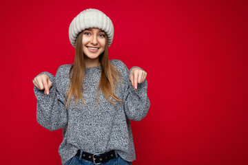 Wall Mural - Photo of young positive happy smiling beautiful woman with sincere emotions wearing stylish clothes isolated over background with copy space and pointing at free space