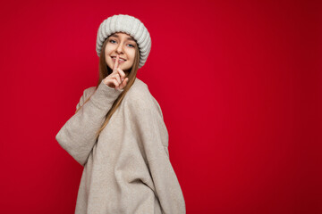 Wall Mural - Photo of young positive happy smiling beautiful woman with sincere emotions wearing stylish clothes isolated over background with copy space and showing shhh gesture