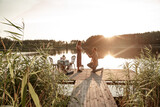 Fototapeta  - Handsome young man requesting hand of beloved pretty girlfriend, asking to marry. Guy standing on his knee during sunset offering engagement ring to surprised woman outside on the forest lake