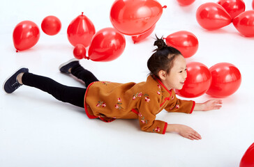 Wall Mural - Cute Asian little girl playing with red festive balloons indoors on white background