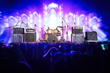 Set of musical instruments during concert with silhouettes of crowd in front of bright stage lights at concert