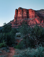 Illuminated Red Rocks In Sedona During Sunset With Green Trees.