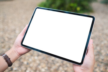 Mockup image of a woman holding digital tablet with blank white desktop screen in the outdoors