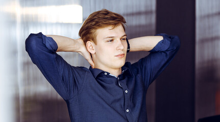 Happy blond businessman and programmer stretching hands after working hard with computer. Startup business leads to success