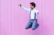 © javiindy - Black man taking a selfie with his smartphone while jumping outdoors.