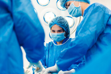 Professional anesthesiologist doctor medical team and assistant preparing patient to gynecological surgery performing operating with surgery equipment in modern hospital operation emergency room