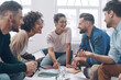 © gstockstudio - Group of modern young people discussing business and smiling while sitting in the office together