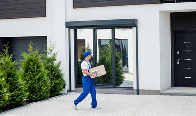 Wall Mural - Young delivery man hold a cardboard box in his hands