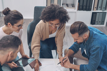 Sticker - Top view of confident business team analyzing data while sitting in the office together