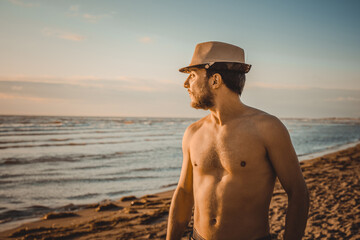 Portrait. Young man watching the sunset on the beach on a day of summer. Concept of thinking and relaxation