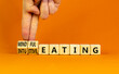 Mindful or intuitive eating symbol. Doctor turns cubes and changes words intuitive eating to mindful eating. Beautiful orange background, copy space. Medical and mindful or intuitive eating concept.