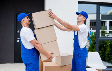 Two removal company workers are loading boxes into a minibus.