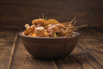 Wall Mural - A deep clay bowl with wild mushrooms on a wooden table.