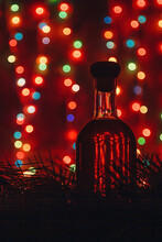 Old Cellar Alcohol Drink Bottle Silhouette On Red Blurry Christmas Background, Shiny Garland Lights Bokeh. Vertical Shot, Copy Space.
