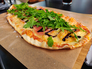 Sticker - Close-up shot of an oval-shaped delicious freshly baked pizza with cheese, bacon ham, and arugula