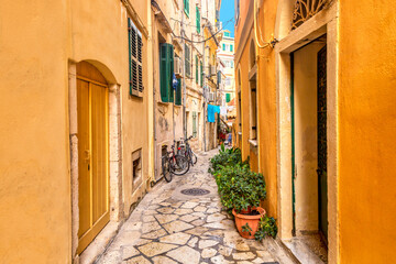 Naklejka na meble Kerkyra city narrow street view with yellow colorful houses and bikes during sunny day. Corfu Island, Ionian Sea, Greece.