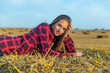 Girl in red shirt sitting on haystack.