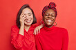 © wayhome.studio  - Indoor shot of overjoyed mixed race young women have fun laugh joyfully show white perfect teeth wear casual clothes isolated over vivid red background. Positive emotions and feelings concept