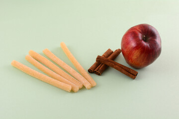 Wall Mural - Apple and cinnamon strudel gummy sticks with fresh apple and cinnamon sticks on light green background