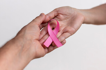 Wall Mural - woman hand with pink ribbon and man hand supporting. pink October. breast cancer awareness campaign. selective focus