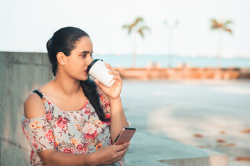 Hispanic woman drinking coffee in the park