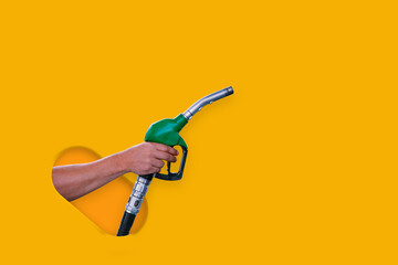 Man holds a refueling gun in his hand for refueling cars isolated on yellow background. Gas station with diesel and gasoline fuel close-up.