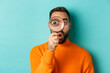 © Mix and Match Studio - Funny man looking through magnifying glass, searching or investigating something, standing in orange sweater against turquoise background