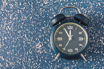 Wall Mural - alarm clock over a cold blue background with scattered snow