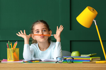 Sticker - Little girl doing homework at table on color background