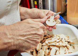 Sticker - Woman cuts mushrooms on wooden cutting board. Cooks according to the recipe at home in the kitchen