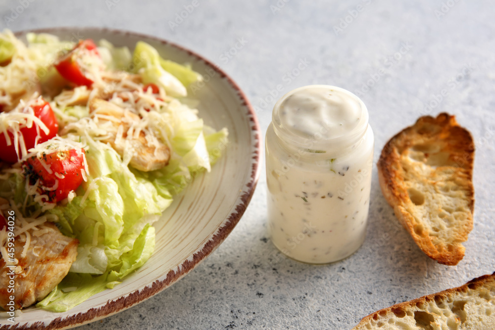 Plate with tasty Caesar salad and sauce on white background, closeup