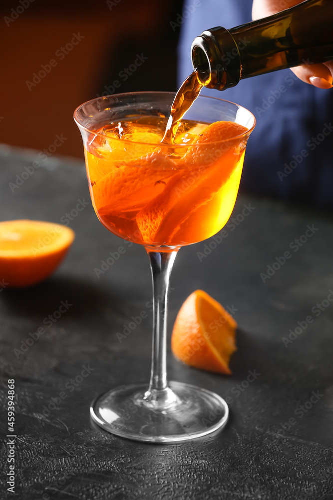 Woman preparing tasty aperol spritz cocktail at table, closeup