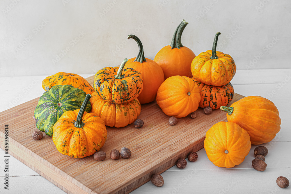 Composition with ripe pumpkins and nutmeg on light background