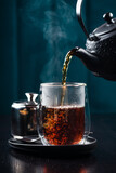 hot tea is poured into a glass with steam