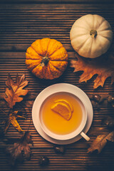 Sticker - Hot lemon tea with fall foliage and pumpkins on wooden background