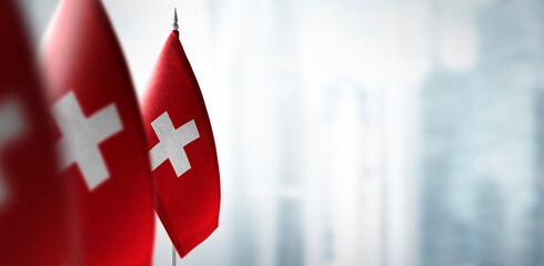 Wall Mural - Small flags of Switzerland on a blurry background of the city