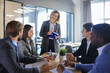© ty - Female boss addressing meeting around boardroom table.