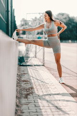 stretching leg muscles in training. a woman in tight fitness clothes stretches her leg muscles durin