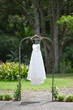 Elegant white bridal dress hanging from a hanger in the garden